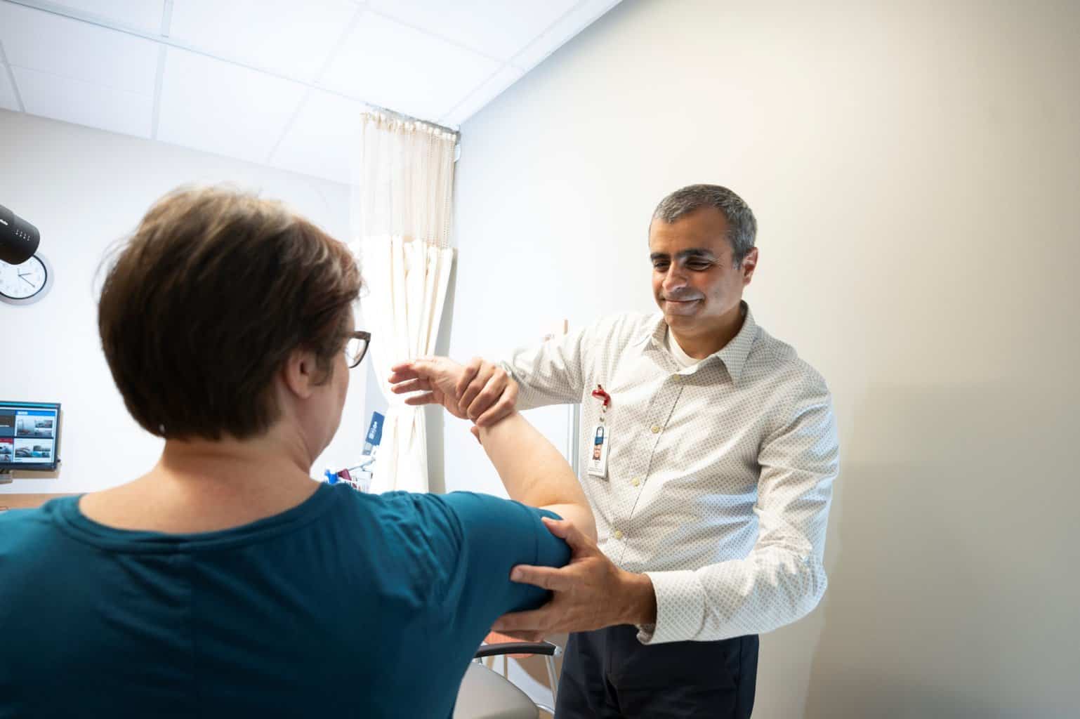 rheumatologist dr nasr performing range of motion on shoulder and elbow of middle aged female patient