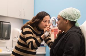 dermatologist at north loop clinic evaluating a mole on patient's face