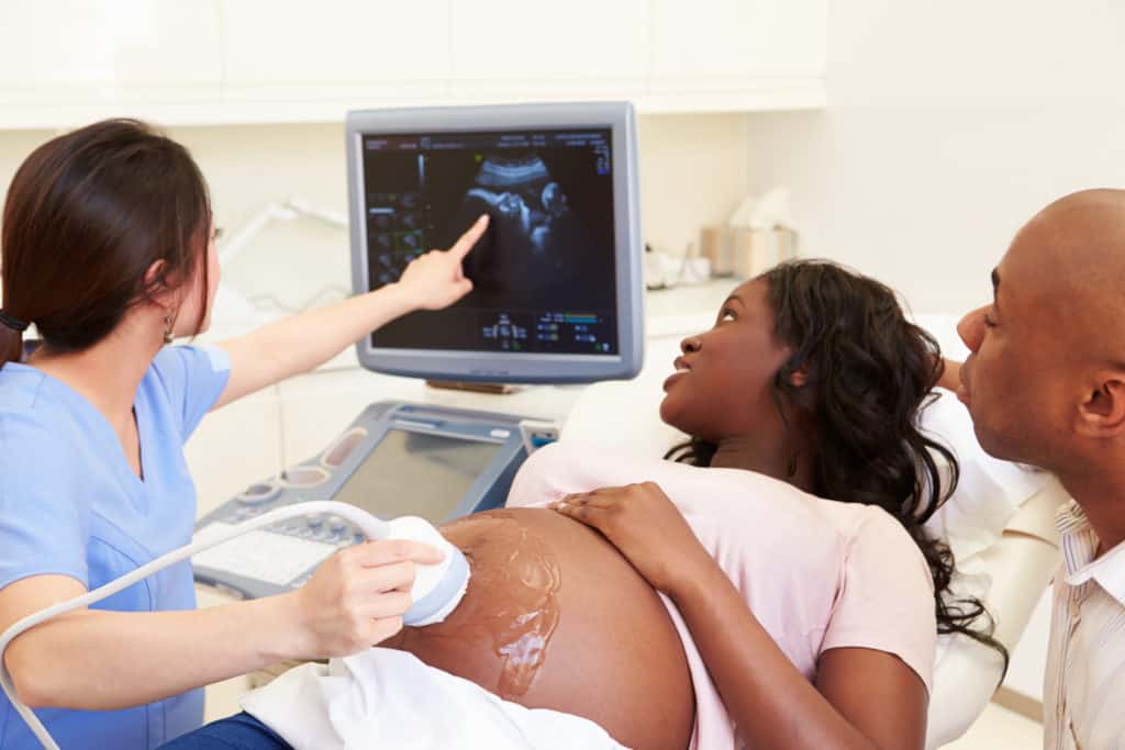 young parents with tech looking at sonogram