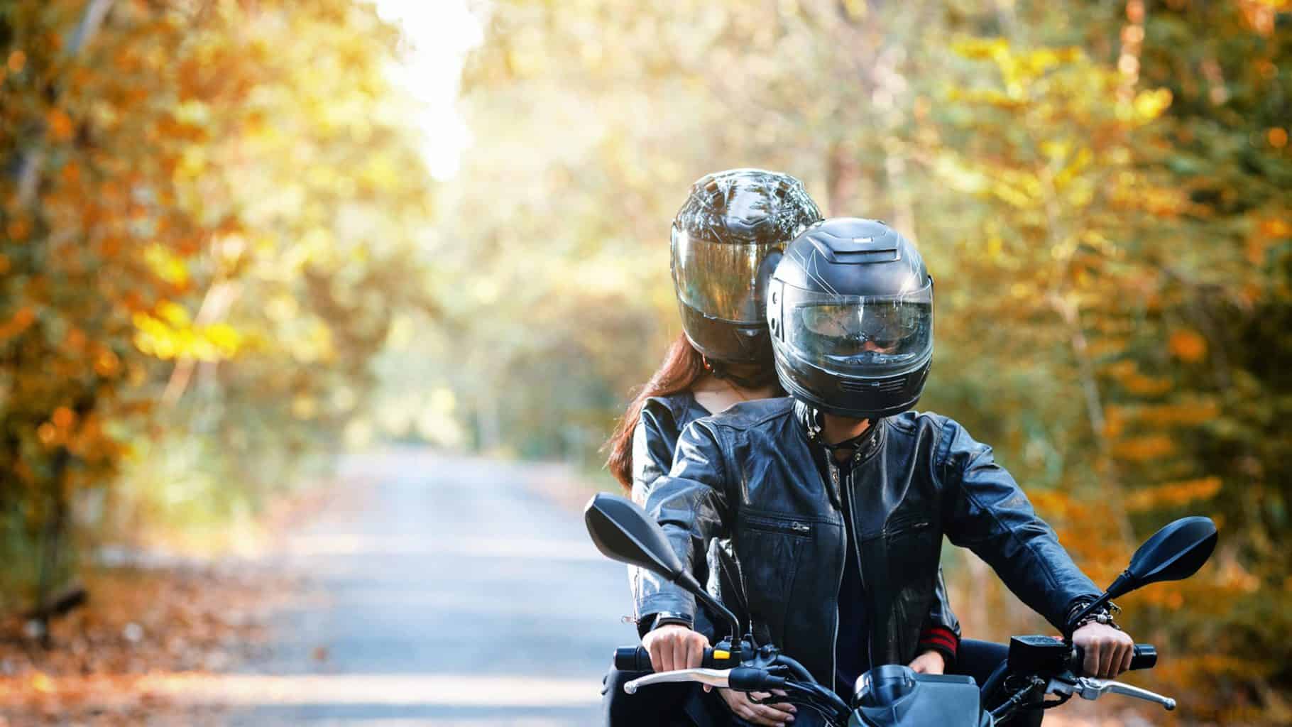 Two people with helmets on motorcyle