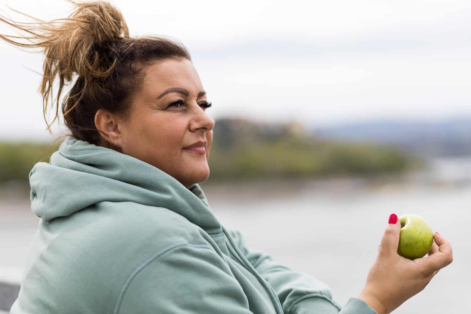 overweight woman eating an apple