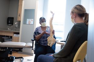 chiropractors at back and neck clinic showing spine model patient