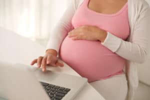 Pregnant woman working on laptop at home, birthing videos, childbirth video, childbirth videos, childbirth education, childbirth education videos