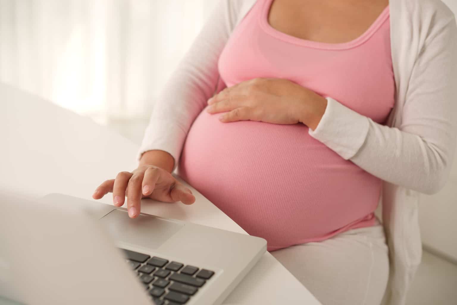 Pregnant woman working on laptop at home