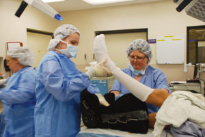 podiatric surgery doctor and tech wrapping patient foot after surgery