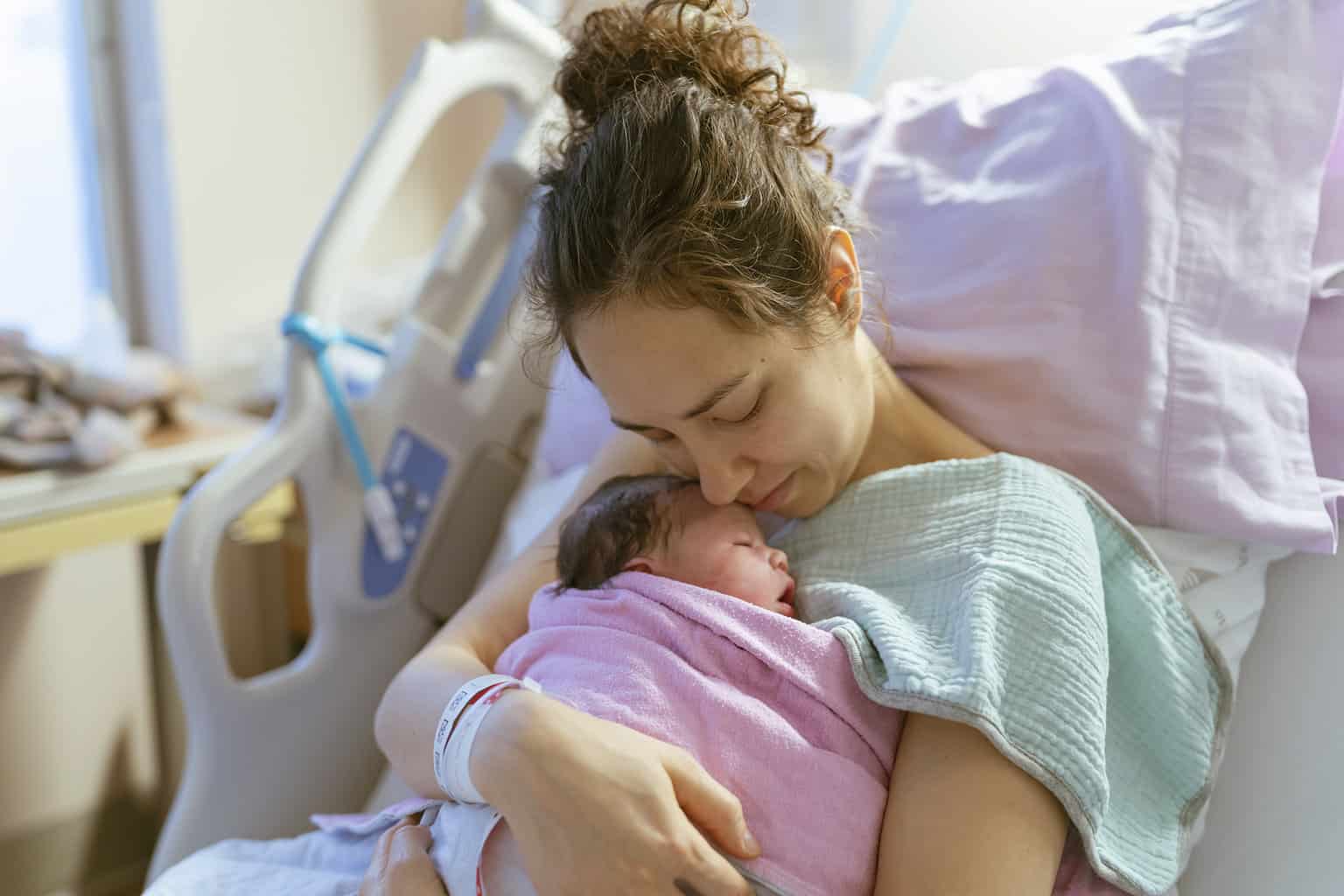 Young Mom with Newborn Baby in Hospital Bed