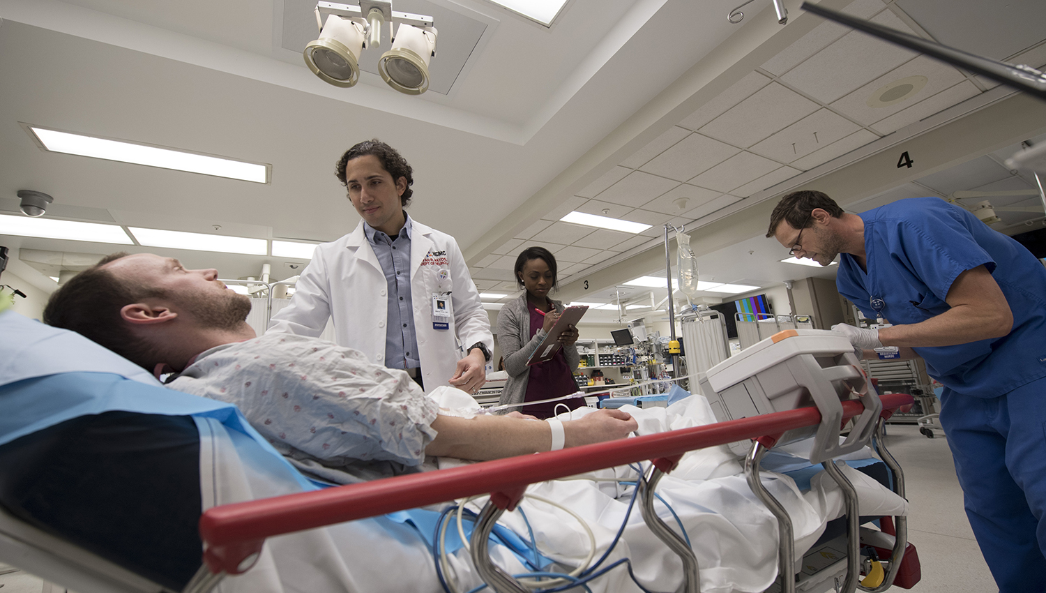 emergency medicine providers assisting patient in bed