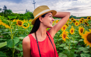 young woman in sunflower field with hat