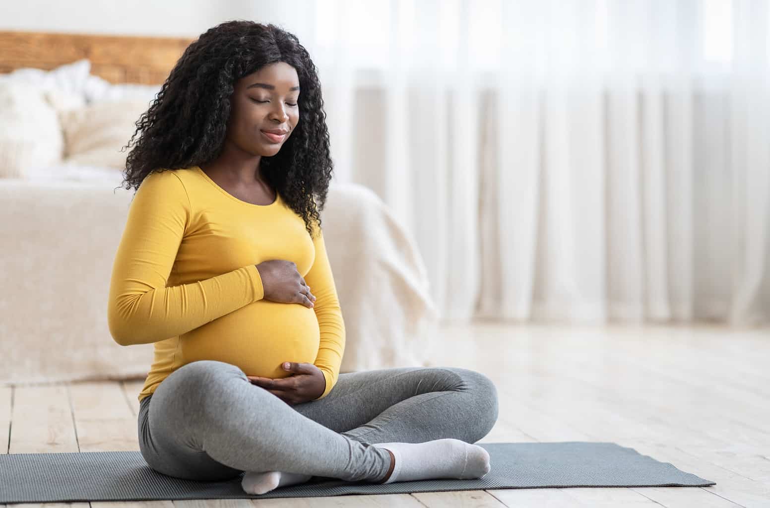 Young Pregnant Woman Sitting on Yoga Mat, pre natal care, prenatal care, prenatal health, emergency medical for pregnancy, at home prenatal care