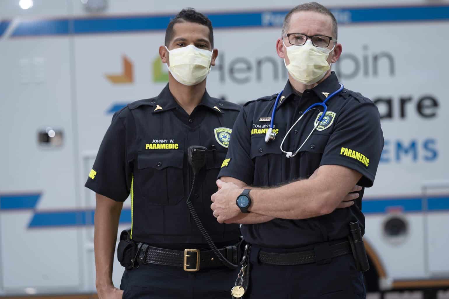 paramedics wearing masks standing in front of ambulance