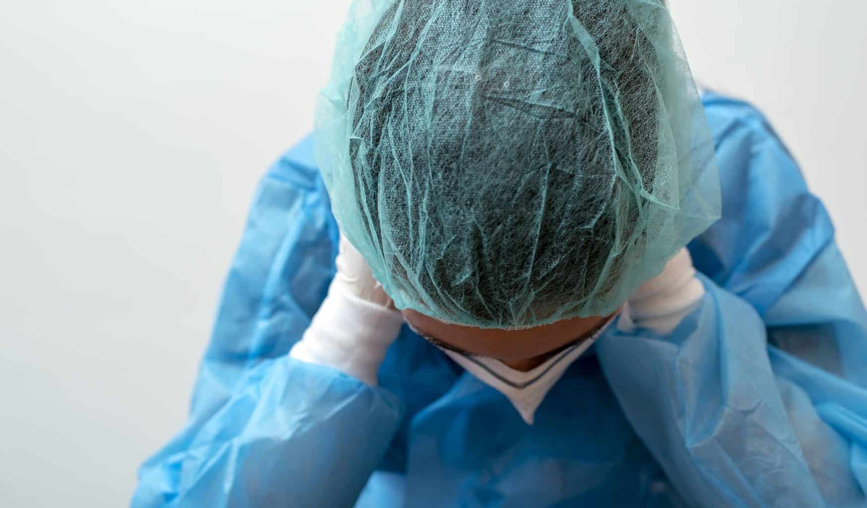 surgery provider with hair net and full scrubs leaning over