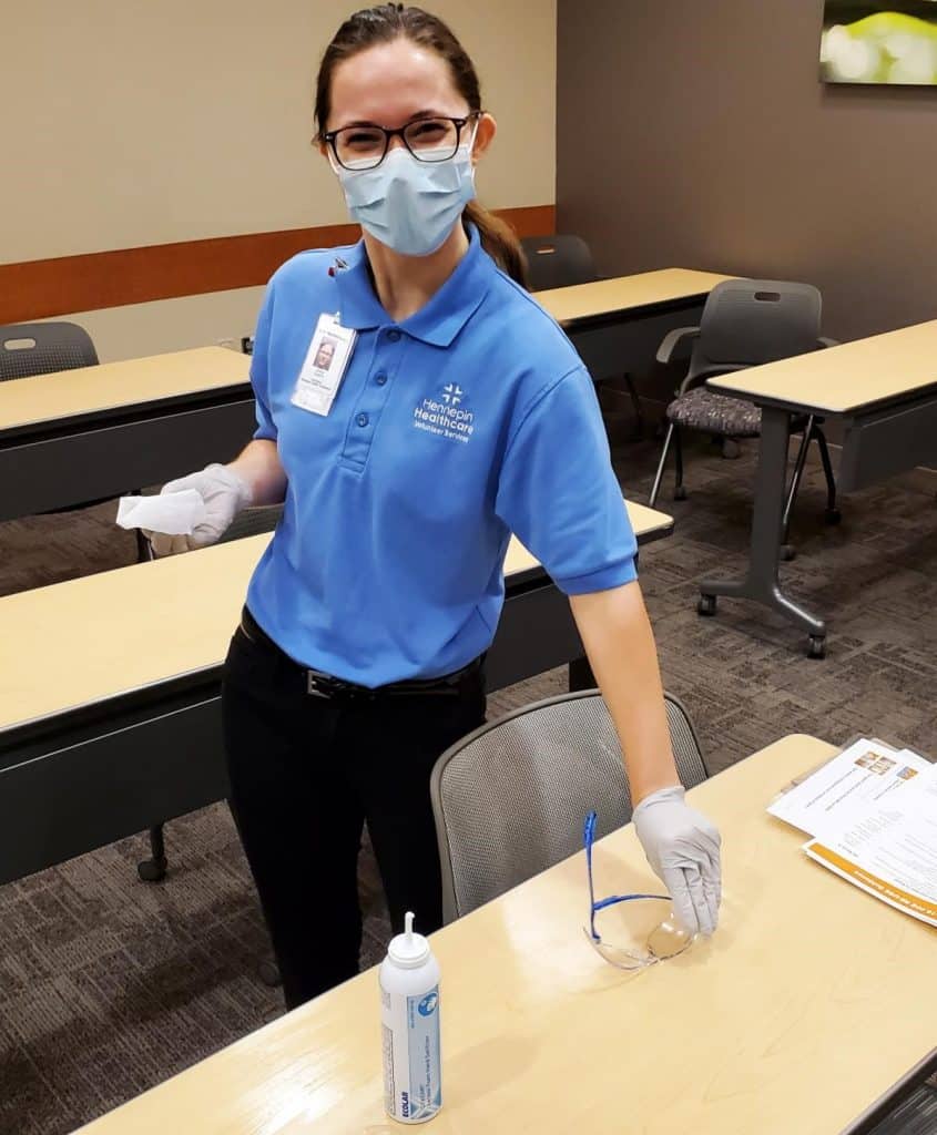 female volunteer cleaning tables and wearing mask