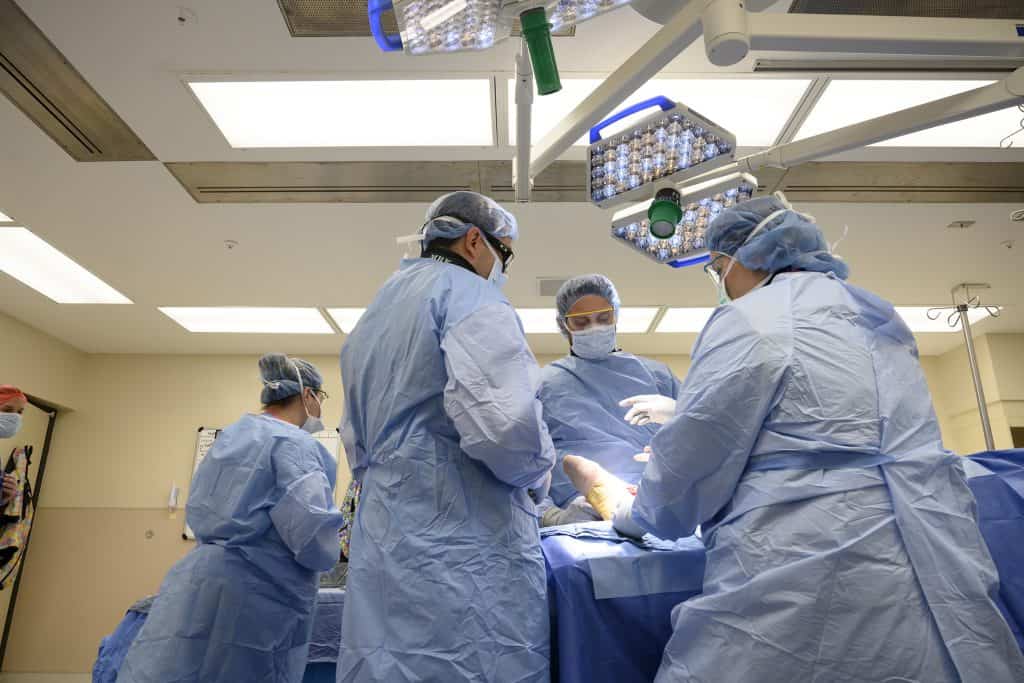 four surgeons in operating room with patient