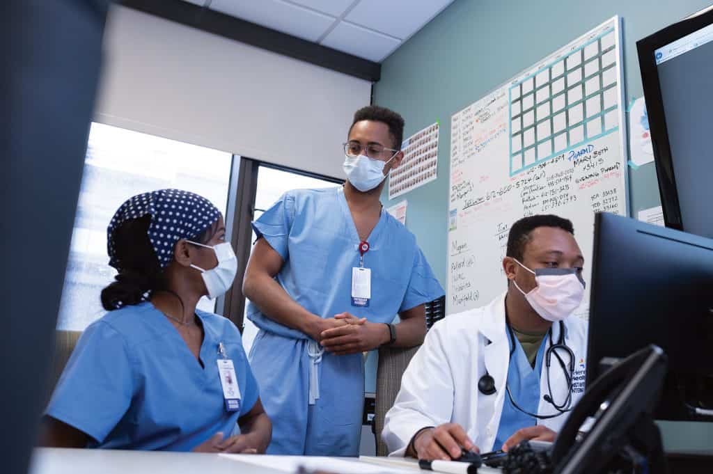 black residents with masks at computer discussing patient case