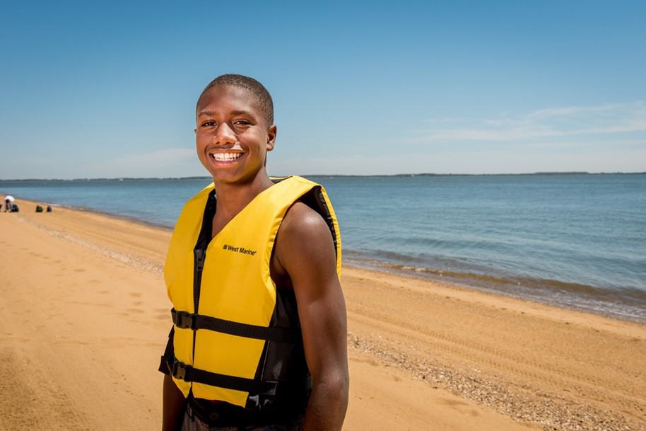 Black young teen boy on beach with life jacket
