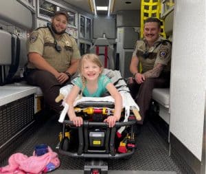 cora with paramedics in ambulance, paramedics re-unite with 5-year old Cora a lucky girl, hennepin ems paramedics, scotty crawford, nick linder, pediatric level one trauma center