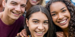 three smiling teens, healthcare that gives adolescents and young adults a voice, rapid socioemotional development, freedom to make decisions, facilitating parent-teen communication, janna gewirtz o’brien