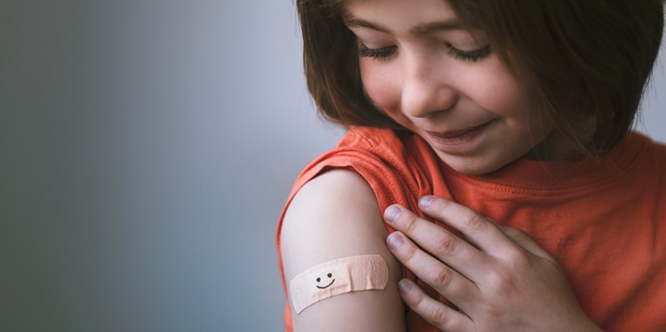 young girl looking at her arm with a bandaid after getting a covid vaccine, childhood vaccinations, vaccines for kids, teen vaccines, covid vaccine, covid prevention for children