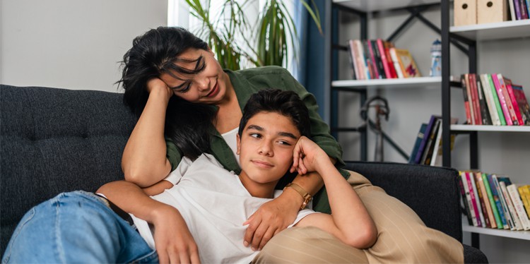 parent with teen lounging on couch, teen relationships, how to discuss teen relationships, unhealthy teen relationships, tips on how to talk about teen relationships