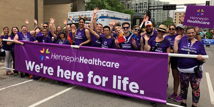 hennepin healthcare employees at pride festival holding purple banner, celebrate pride month with hennepin healthcare, gay pride, pride festival, celebrating pride, lgbtq pride month