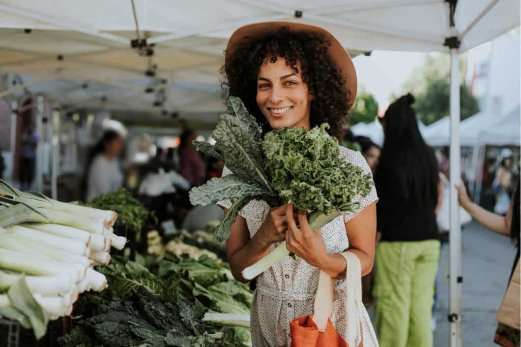 woman holding bushel of kale at farmer's market, preserving food for winter, tips for saving nutrients in food, dr kate shafto, healthy food, nutrition