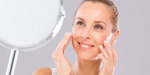 young woman looking in the mirror and smiling that she has healthy skin, microneedling, cosmetic derm, cosmetic dermatology, cosmetic procedure, micro needling
