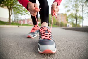 woman outside tying her running shoes, walk with a doc, promote healthy movement, community walks with a doctor, take steps towards a healthier lifestyle, improves brain function