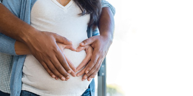 young pregnant woman with her partner holding her belly together, life-changing experience, place to give birth, birth plan, postpartum support, prenatal support, lowest C-section rate, dr tara gustilo, dr laura nezworski, natural birth, pain management options