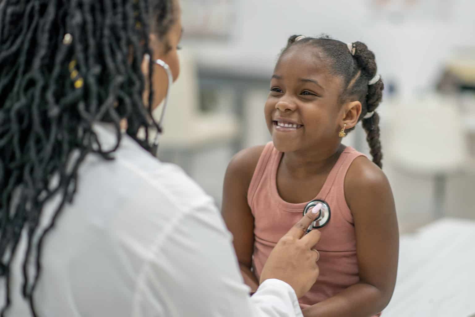 doctor listening to girl's heart with stethoscope