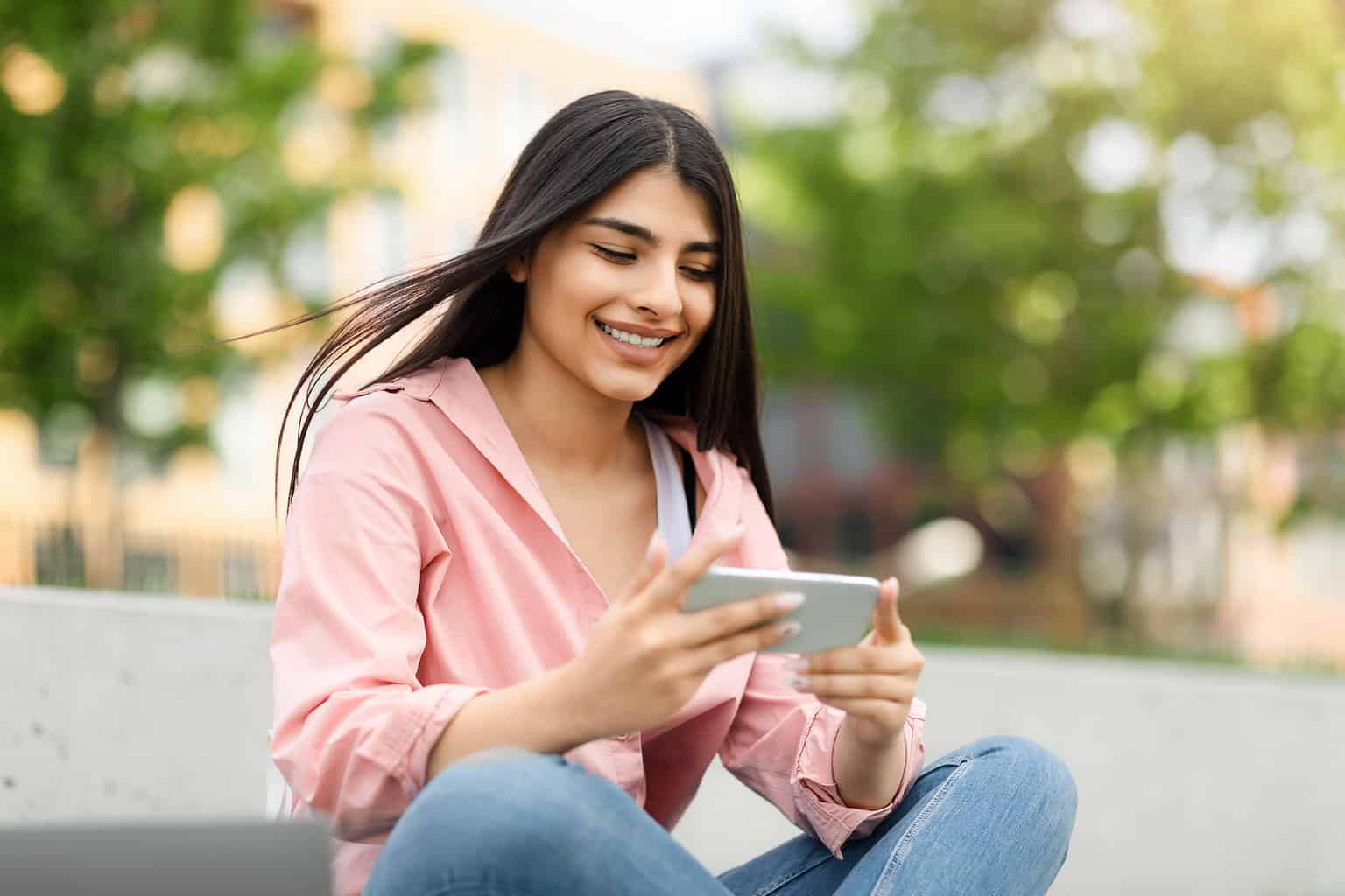 Smiling Teen Hispanic Lady Messaging Or Playing On Smartphone While Relaxing In Park Outdoors, Free Space, mychart