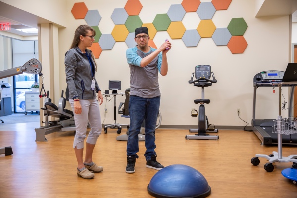 brooklyn park physical therapist with patient in gym, Brooklyn Park Clinic expansion, more health care services and specialists, physical therapy gym, onsite pharmacy, clinic expansion in brooklyn park