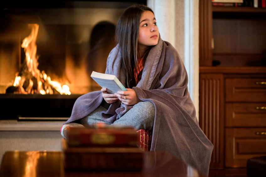 Girl holding a book by the fireplace